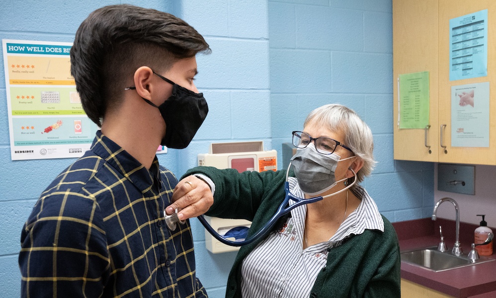 Examining a patient with a stethoscope at Uplift High School